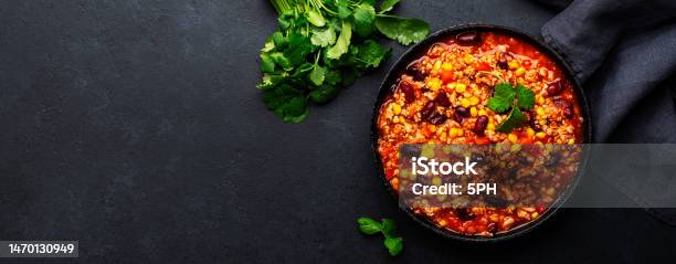 Chili Con Carne With Beef Red Beans Paprika Corn And Hot Peppers In Tomato Sauce Spicy Texmex Dish In A Cooking Pot Black Table Background Top View Banner Stock Photo - Download Image Now