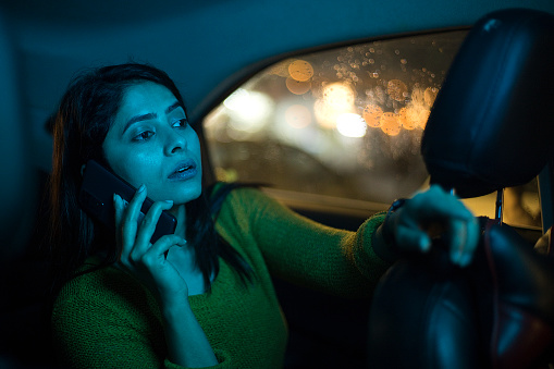 Curious woman talking on mobile phone in back seat of car