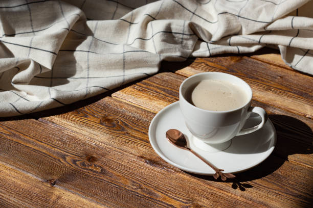 tasse blanche de café au lait ou de cappuccino avec mousse laiteuse sur une table en bois brun avec une table à table sur le côté. - brown table coffee table side table photos et images de collection