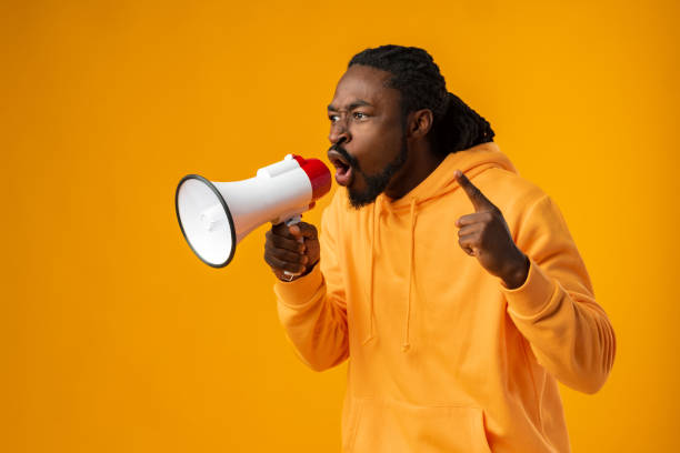 istock Young african man against yellow background with megaphone 1470137156