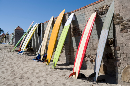 Surf boards leaning on wall near beach in San Diego.