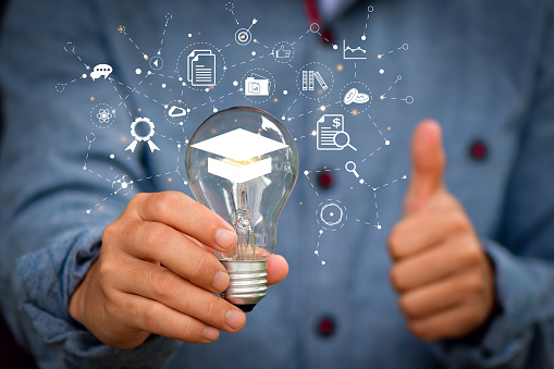 E-learning Education Internet Technology Webinar Online Courses concept. hand holding lightbulb showing graduation hat,