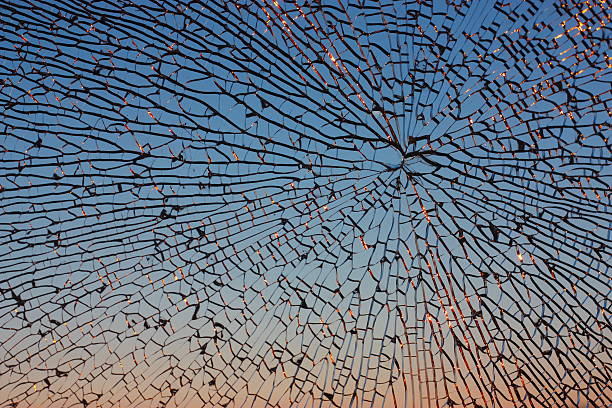 Light reflecting on a shattered house window at sunset.