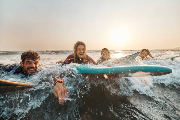 ¡surfeando en el mar al atardecer! - women sea cheerful surfing fotografías e imágenes de stock