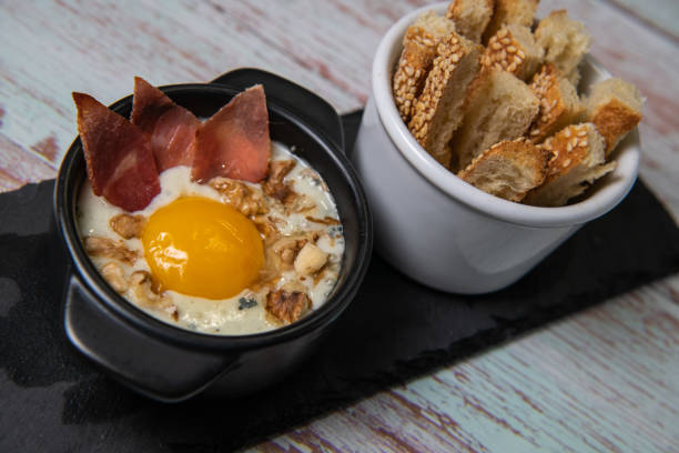 Recipe Oeuf cocotte with fresh cream sauce, Roquefort and walnuts, ham chips, toasted bread sticks