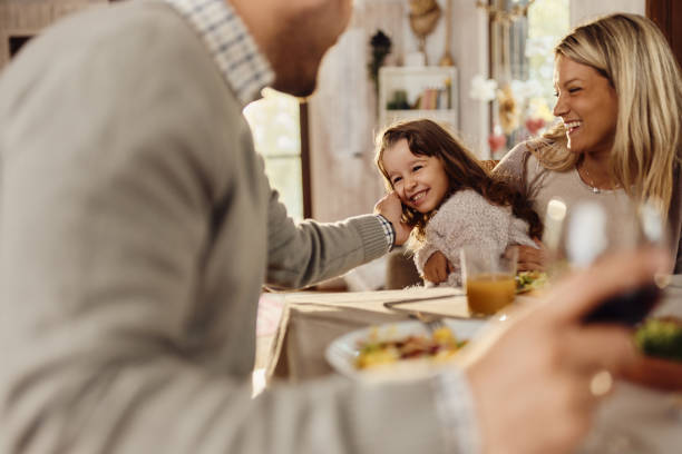 istock Cheerful mother and daughter enjoying with father at dining table. 1470146786