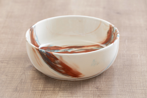 ceramic multicolored bowl close up on wooden table