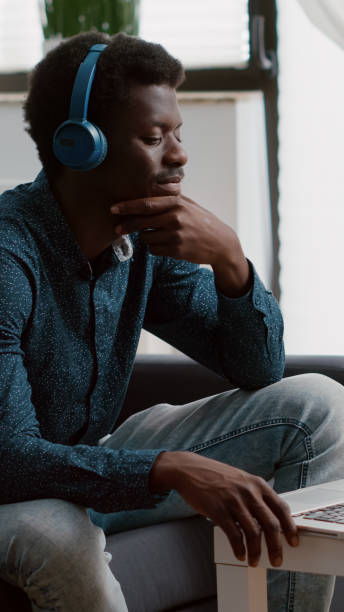 istock Authentic smiling african american man using laptop with headphones on, working from home 1470153928