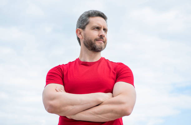 istock confident guy in red shirt crossed hands on sky background 1470154069