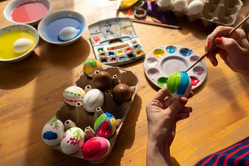 Woman painting easter eggs, easter decoration on table