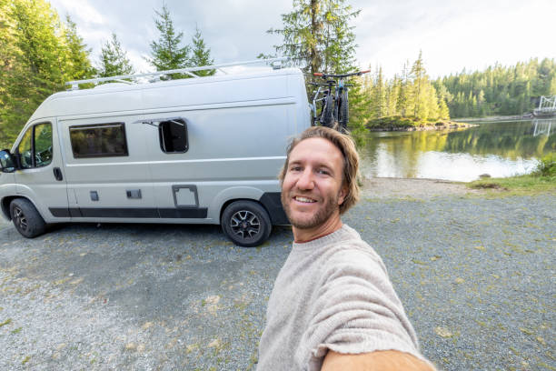 People travel, alternative homes concept. He smiles at the camera, happy to be traveling. He wears a wool hat