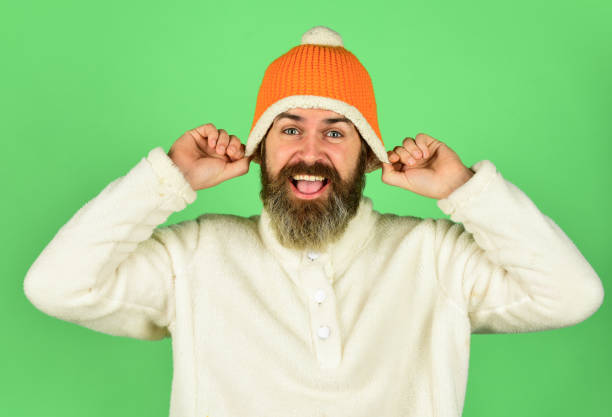 Feeling good. Bearded hipster. Hipster style. Head in warm hat. Handsome man knitted hat with pom pom. Fashion concept. Winter clothes and accessories. Mature emotional hipster funny style accessory.