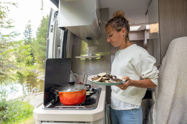 istock Woman cooking in her van, lake view 1470157375