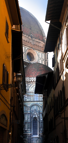 Cathedral Santa Maria del Fiore seen between two buildings, on a small street, Florence, Italy