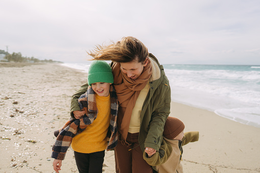 Photo of two young boys and their mom spending windy, winter day at the local beach