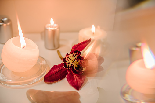 Spa center. Details decor in spa salon. Gua sha tool. Candles, and orchid flowers on table. Facial massage for lifting, face therapy. Skincare concept. Cosmetology, body massage, spa procedure.