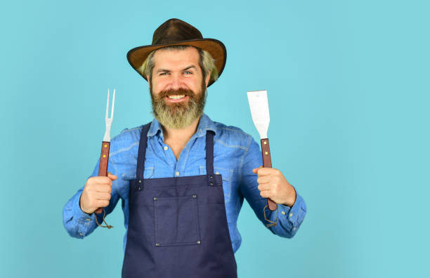 istock summer weekend. happy hipster hold cooking utensils for barbecue. bearded man chef. Tools for roasting meat outdoors. Picnic and barbecue. ready for barbecue party. Culinary concept. copy space 1470158473