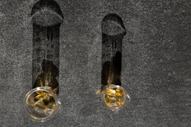Cod Liver Oil.Fish oil capsules in laboratory flasks on a black slate background in bright hard light with shadows.Omega-3.omega fatty acids.Natural supplements