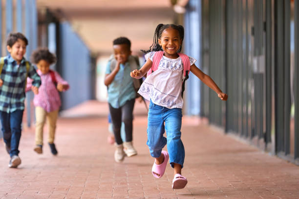 istock Group Of Multi-Cultural Elementary School Pupils Running Along Walkway Outdoors At School 1470158744