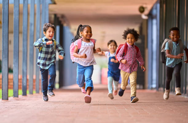 grupo de alunos multiculturais do ensino fundamental correndo ao longo da passarela ao ar livre na escola - childhood - fotografias e filmes do acervo