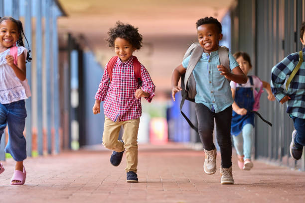 istock Group Of Multi-Cultural Elementary School Pupils Running Along Walkway Outdoors At School 1470158907