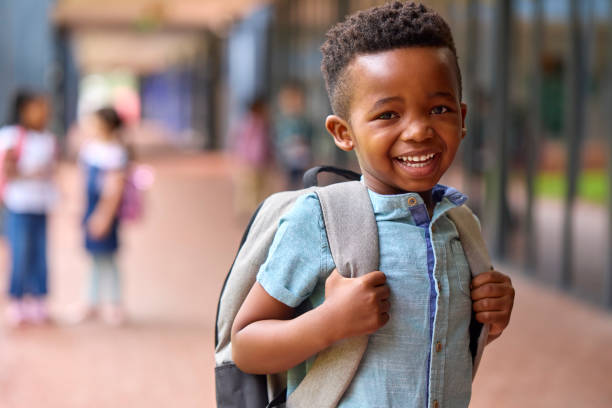 Ritratto dell'alunno sorridente della scuola elementare maschile all'aperto con lo zaino a scuola - foto stock