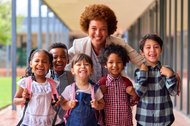 Ritratto di alunni della scuola elementare multiculturale con insegnante femminile all'aperto a scuola - foto stock