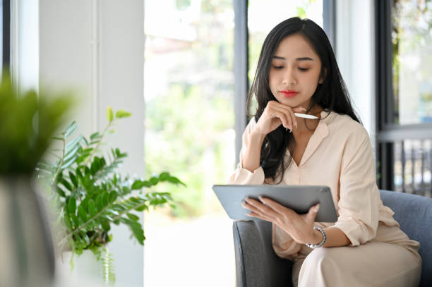 istock Professional Asian businesswoman using digital tablet, pensively thinking and pondering 1470160425