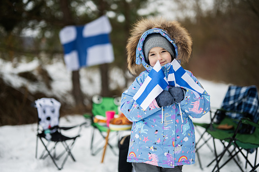 Finnish little girl with Finland flags on a nice winter day. Nordic Scandinavian people.