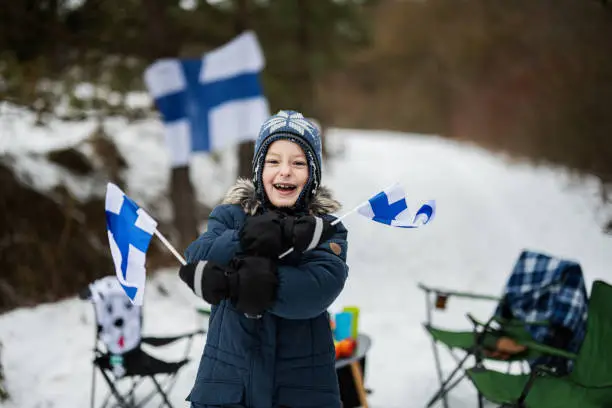Photo of Finnish boy with Finland flags on a nice winter day. Nordic Scandinavian people.