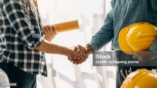 Construction Team Shake Hands Greeting Start New Project Plan Behind Yellow Helmet On Desk In Office Center To Consults About Their Building Project Stock Photo - Download Image Now