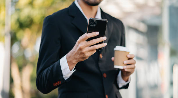 istock Asian businessman using digital tablet, smartphone and holding coffee to go while working at office 1470161642