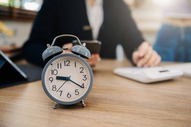 istock Alarm clock on the desk. Business working in modern office building or home at night using laptop. 1470161801