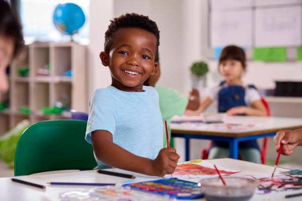 Retrato da sala de aula do aluno sorridente do ensino fundamental masculino na aula de arte na escola - foto de acervo