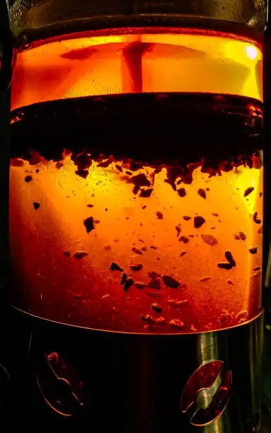 Close-up shadow view of coffee grounds that are being filtered start to fall to the bottom with orange-color background light