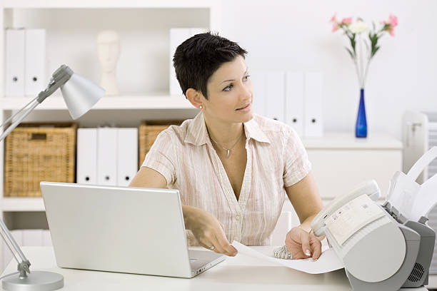 Woman using fax machine stock photo