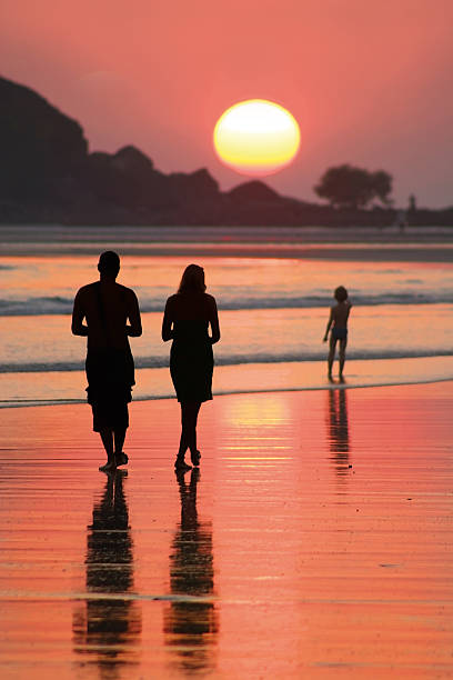 Family walking on beach at sunset family goes for a walk on a beach on sunset palolem beach stock pictures, royalty-free photos & images
