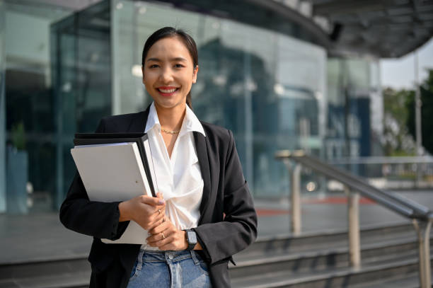 istock Confident Asian businesswoman holding document folders, smiling, looking at camera 1470164013