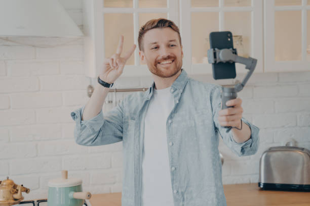 istock Handsome smiling young brunete man with stubble making selfie in kitchen 1470164207