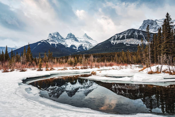 istock Three Sisters Mountains with snow covered on bow river reflection in the morning on winter at Canmore 1470166484