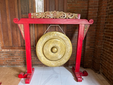 Traditional music instrument named Gong with golden metal plate hanging on wooden frame.