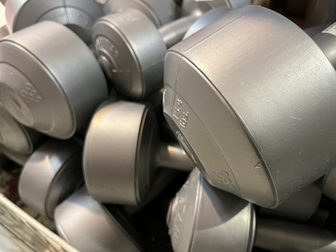 Close up view of messy stack of plastic dumbbells with various weights being displayed in a store.