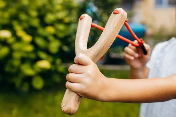 Close up wooden slingshot toy in hands of little girl