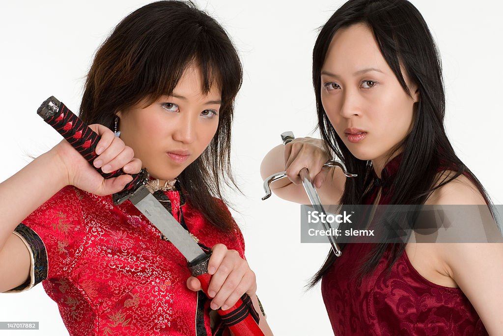 Sword Strike Attractive young Asian women, bearing a samurai sword, preparing to strike. Adult Stock Photo