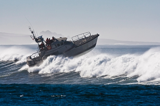 Coast Guard boat (identifying marks removed) battles storm waves during open ocean water rescue survival maneuver near Morro Bay, CA, off the west coast of the USA.