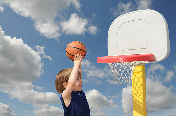 Striving A little boy reaches up to put his basketball in the hoop, confident of his success toddler hitting stock pictures, royalty-free photos & images