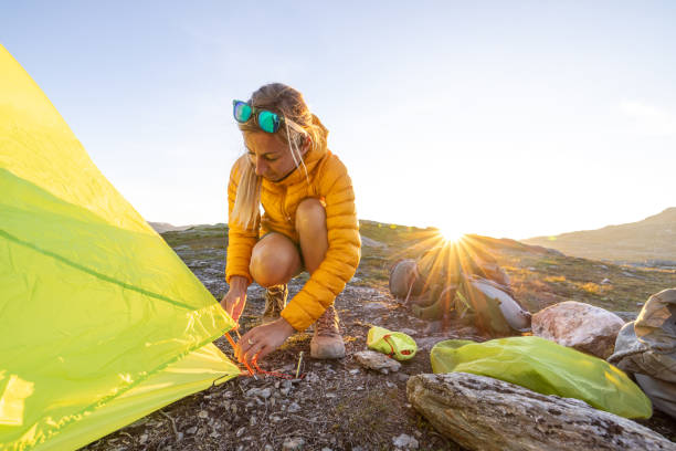 istock Woman setting up tent outdoors in Norway 1470197735