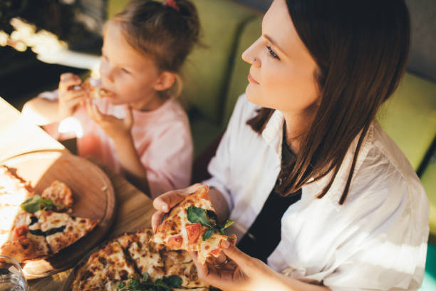 istock Mother and daughter eat pizza in a cafe. 1470197930