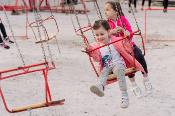 istock Carefree girls having fun while riding on chain swing at amusement park 1470198632