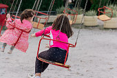 Carefree girls having fun while riding on chain swing at amusement park